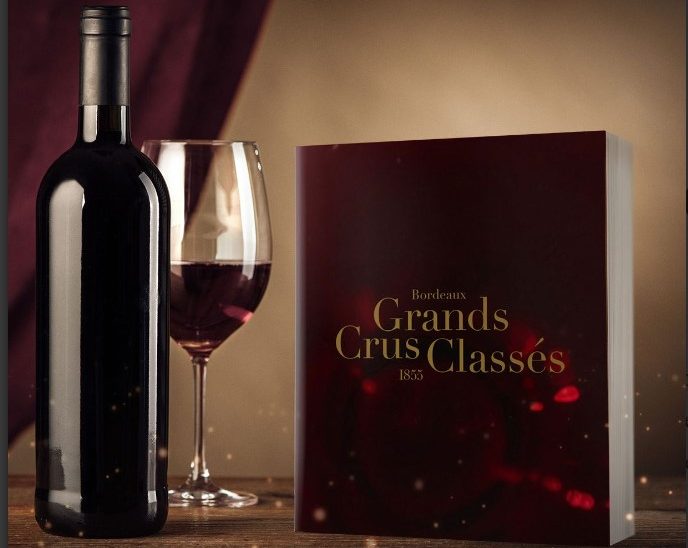 Bok med teksten Grands Crus Classes" står ved siden av en vinflaske og et glass rødvin