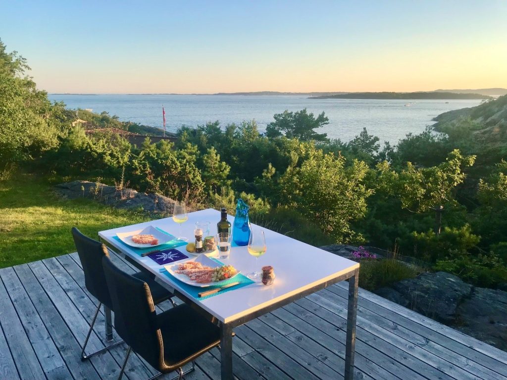 Et dekket bord med to stoler på en verandaplatting med utsikt mot sjøen